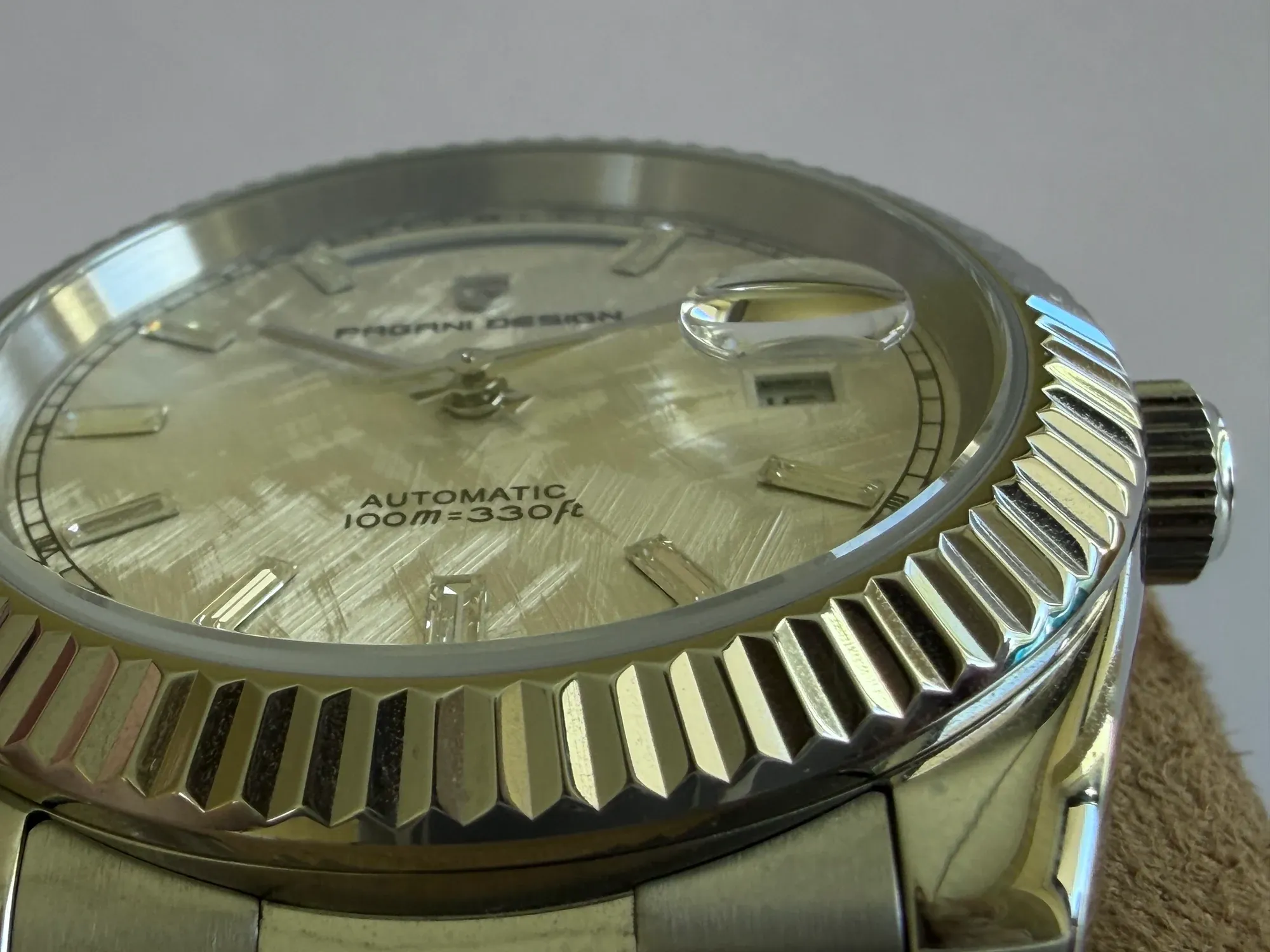 Low angle across the crystal, showing the raised cyclops over the date and the fluted bezel.